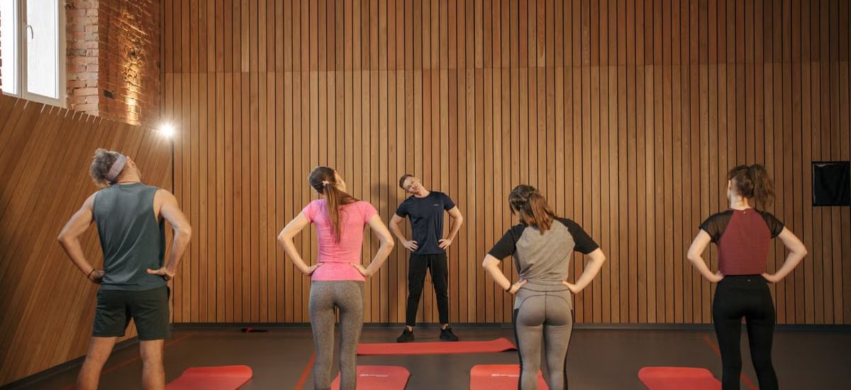 Men and women performing stretching exercises on mats in a fitness class