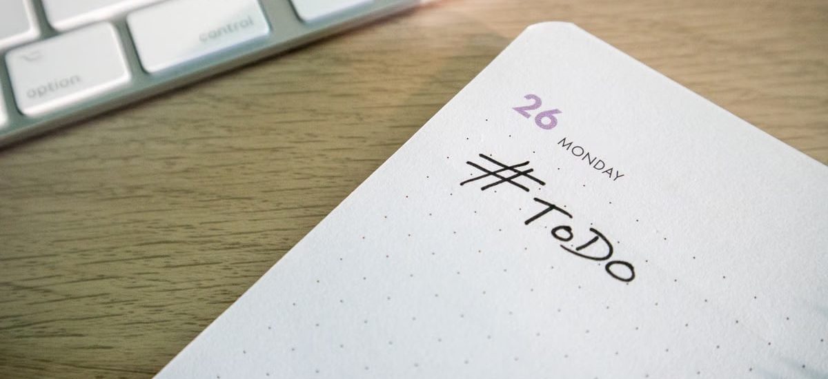 Close-up of a to-do list next to a computer keyboard on a desk.