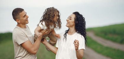 A joyful family moment outdoors with parents playing with their daughter.